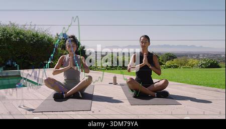 Due donne sedute a meditare sul ponte in legno a bordo piscina con top sportivi con tappetini e bottiglie Foto Stock