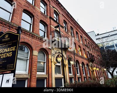 Manchester, Regno Unito - 21 gennaio 2026: Fila di case a schiera di mattoni rossi con finestre ad arco e classici lampioni stradali a Manchester, Regno Unito. Foto Stock
