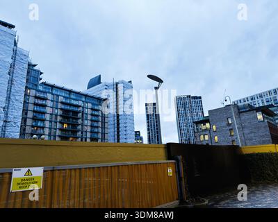 Manchester, Regno Unito - 21 gennaio 2026: Costruzione urbana a Manchester Regno Unito con barriera gialla, edifici alti e cielo nuvoloso. Foto Stock