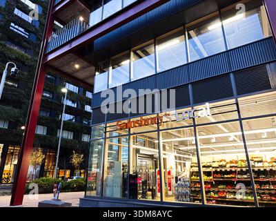 Manchester, Regno Unito - 21 gennaio 2026: Vetrina locale di Manchester Sainsbury con facciata in vetro e illuminazione interna brillante. Foto Stock