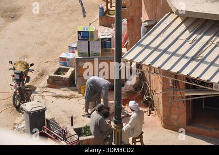 Gli uomini si riunirono e lavoravano fuori dal negozio sulla strada visto dall'alto Foto Stock