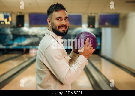 Tenendo la palla, in piedi. L'uomo gioca a bowling al chiuso. Foto Stock