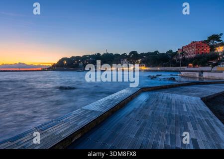 Vista serale di una piattaforma in legno sul lungomare di Castiglioncello. Tramonto sulla costa mediterranea, Toscana, Italia Foto Stock