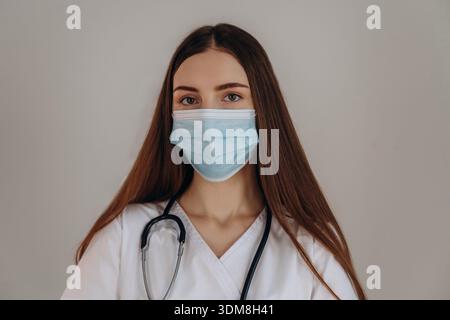 Con maschera facciale. La dottoressa donna è nello studio. Foto Stock