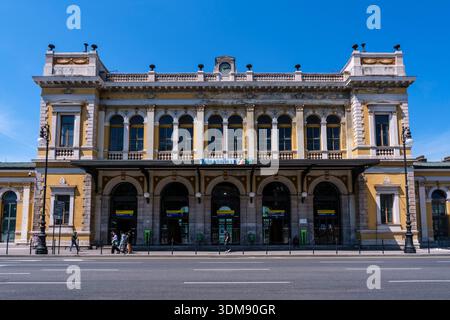Vista frontale della stazione ferroviaria di Trieste centrale con la sua facciata neoclassica sotto un cielo azzurro. Foto Stock