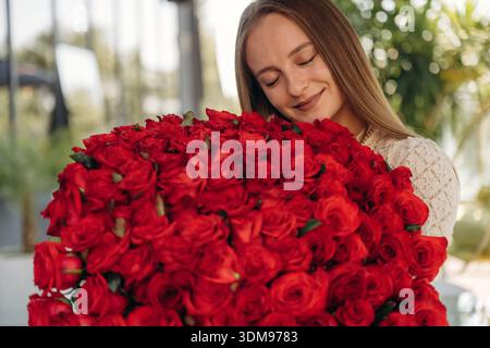 La giovane donna felice è con un grande bouquet di rose. Foto Stock