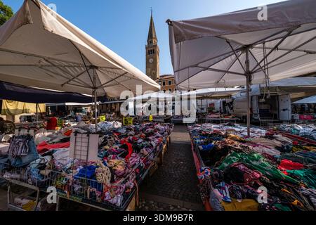 Mercato settimanale con bancarelle di abbigliamento in Piazza della Repubblica. La chiesa di Sant'Andrea Apostolo è visibile in lontananza sotto un cielo azzurro. Foto Stock