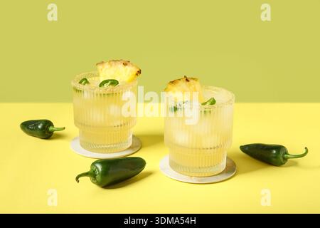 Bicchieri di gustoso cocktail di margarita con pepe jalapeno e ananas su sfondo colorato Foto Stock