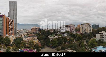 Panorama urbano con alti edifici moderni e montagne sullo sfondo in una giornata nuvolosa. Tirana, Albania Foto Stock