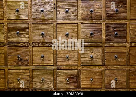Un tradizionale armadietto cinese in legno dalle calde tonalità marroni si erge con i suoi numerosi piccoli cassetti quadrati disposti in perfetto ordine. Foto Stock