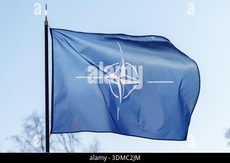 La bandiera della NATO sventolava nel vento contro un cielo azzurro. Foto Stock