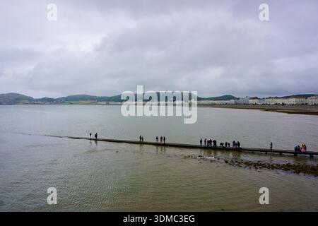 Persone in piedi sul molo di Llandudno che si affaccia sulla baia di Llandudno, Galles del Nord, Regno Unito Foto Stock
