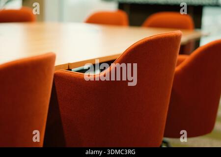 Sala meeting per conferenze con posti a sedere all'interno. Spazio ufficio professionale con sedie imbottite allineate intorno al tavolo in legno per creare un ambiente strutturato Foto Stock