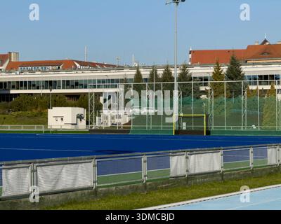 Poznan, Polonia - 18 novembre 2025: Un chiaro complesso sportivo all'aperto con un campo da hockey su prato blu, un gol giallo e una rete di sicurezza, perf Foto Stock