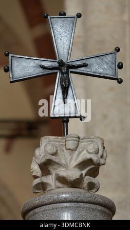 Crocifisso in bronzo su un capitale in pietra all'interno della Basilica di Santambrogio, Milano, Italia. Arte e architettura romanica. Foto Stock