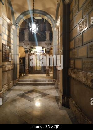Fotografia verticale di un'antica e bellissima entrata di un edificio residenziale di Barcellona. Pavimento e decorazioni in marmo, soffitto alto e una i battuto Foto Stock