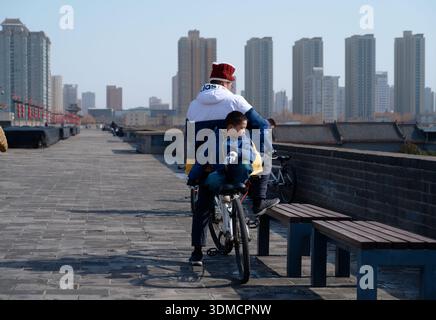 Padre e figlio si fermano in bicicletta in cima alle mura della città di Xi'an, prendendo un momento tranquillo per ammirare il panorama Foto Stock