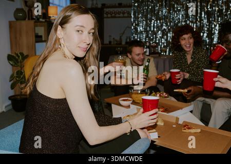 Ritratto di una giovane donna caucasica che sorride mentre festeggia con gli amici Foto Stock