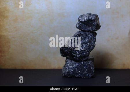 Rocce laviche grezze impilate delicatamente in una composizione verticale che simboleggia la stabilità e la messa a terra interna. Foto Stock