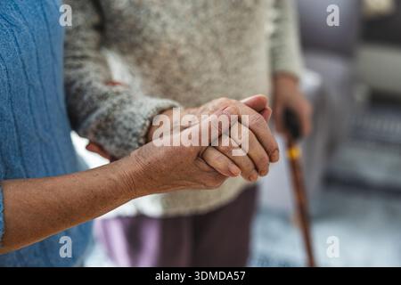 Donna anziana che si tiene per mano con il suo assistente in una casa di cura, da vicino Foto Stock