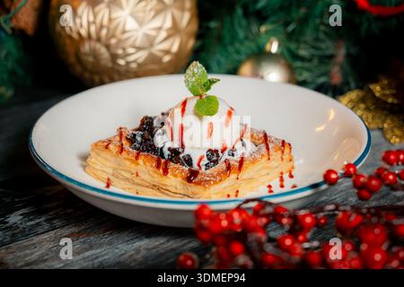 Un dessert con una foglia verde sopra e una paletta di gelato. Il dessert è servito in una ciotola bianca Foto Stock