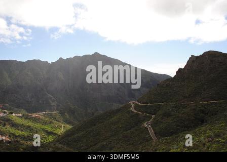 Panorama della valle di Masca con terrazze e la strada tortuosa al sole Foto Stock