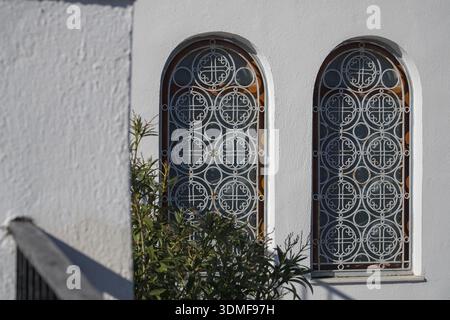 Chiesa metropolitana della presentazione del Signore, Fira, Santorini, Grecia. Primo piano di griglie di sicurezza in ferro battuto bianco ornato su finestre ad arco Foto Stock