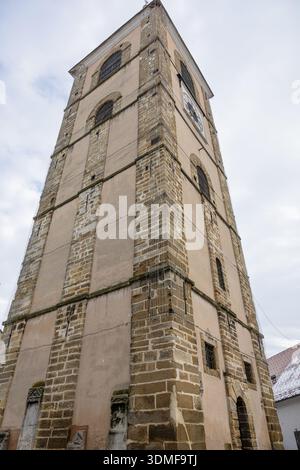 Un'alta torre dell'orologio caratterizzata da mattoni e murature in pietra, finestre ad arco e una grande faccia dell'orologio. La storica architettura europea aggiunge carattere al cit Foto Stock