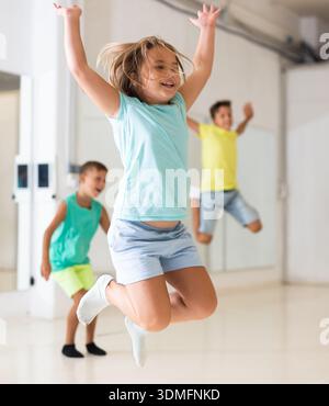 Ragazza felice di Tween che saltano insieme ai bambini nello studio coreografico Foto Stock
