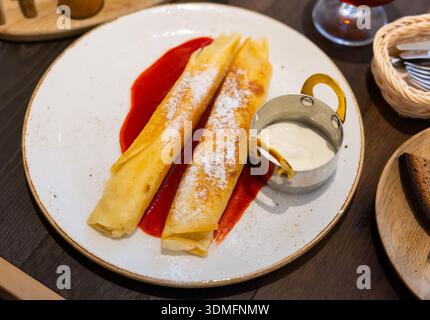 Il dessert nel ristorante è costituito da due pancake arrotolati, ripieni di cagliata Foto Stock