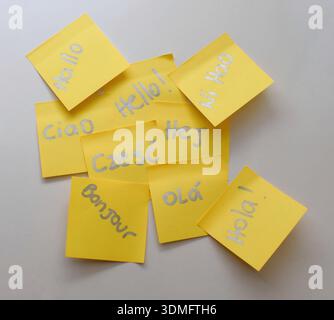 Fotografia di alta qualità di note gialle poste disposte su un tavolo bianco pulito, ciascuna con la parola "Hello" scritta in diverse lingue. Perfe Foto Stock