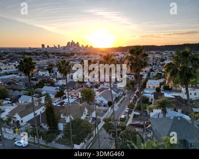 Tramonto dorato con palme classiche in vista in primo piano dello skyline del centro di Los Angeles in lontananza all'orizzonte Foto Stock