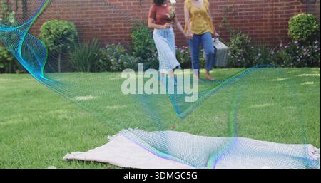 Donne che camminano mano in mano sul prato del giardino, indossando ruggine, top di senape con cesto, copertura in rete color ottanio Foto Stock