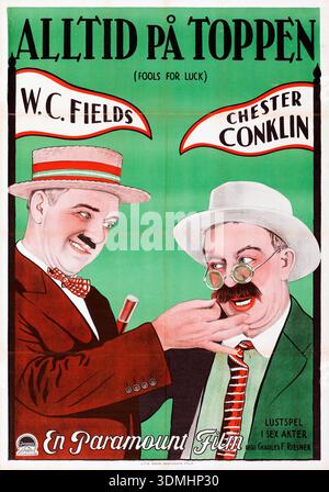 Questo vivace poster cinematografico svedese del 1928, intitolato "Alltid på Toppen" (folli per la fortuna), presenta caricature dei comici di Hollywood W. C. Fields e Chester Conklin. Fields è raffigurato in una tuta rossa che regola i baffi di Conklin, che indossa una giacca verde e occhiali rotondi, evidenziando la loro dinamica comica in questo film della Paramount. Foto Stock