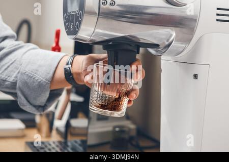 Macinatura di caffè di alta qualità in una macchina elettrica professionale in una caffetteria Foto Stock