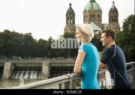 Giovane coppia atletica che riposa sul ponte che si affaccia sul fiume Foto Stock