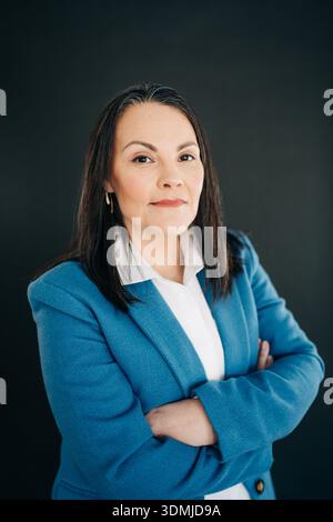 Donna professionista che indossa un blazer blu che incrocia le braccia Foto Stock