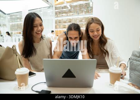 Amici eterogenei che apprezzano i contenuti sul notebook insieme Foto Stock