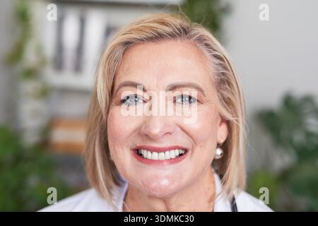 Medico femminile amichevole Ritratto sorridente in cappotto bianco per uso sanitario e professionale Foto Stock