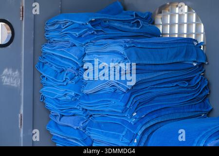 Una pila di asciugamani blu ben piegati all'interno di un vano portaoggetti con un'apertura circolare visibile sullo sfondo Foto Stock