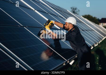Ingegnere solare maschio che esamina i pannelli fotovoltaici in una centrale elettrica. Foto Stock