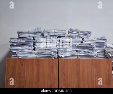 Pile di carta bianca legate con fascette in gomma sulla parte superiore di Un armadietto di legno per l'amministrazione e la documentazione dell'ufficio Foto Stock