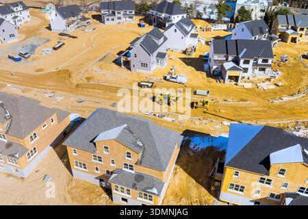 I lavoratori edili stanno costruendo nuove case in un'area suburbana con macchinari pesanti e materiali da costruzione. Foto Stock
