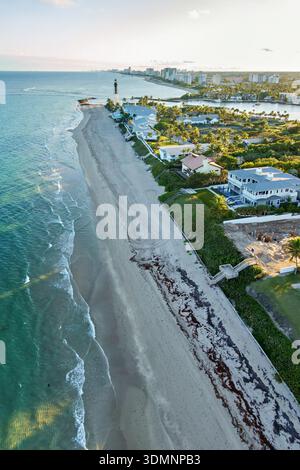 Vista aerea della costa dove l'oceano turchese incontra la spiaggia sabbiosa, contrastando con la vegetazione verde e gli edifici sparsi, Deerfield Foto Stock