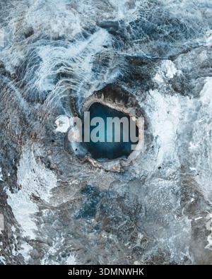Vista aerea della sorgente calda blu vibrante immersa nel paesaggio ghiacciato, Geysir, Bláskógabyggð, Islanda. Foto Stock