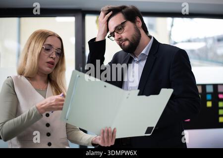 Colleghi che discutono di documenti durante una riunione sul luogo di lavoro in un ambiente di ufficio moderno Foto Stock