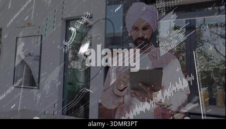 Analisi di un uomo con turbante rosa e camicia a scacchi che regge il tablet in una finestra di vetro con sovrapposizioni di dati Foto Stock