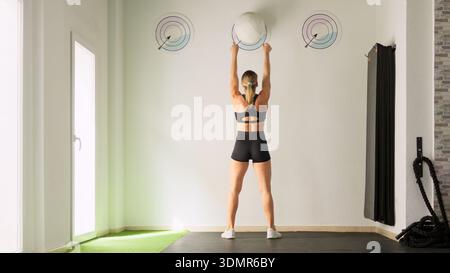 Donna che si allena con palla medica nella palestra fitness Foto Stock
