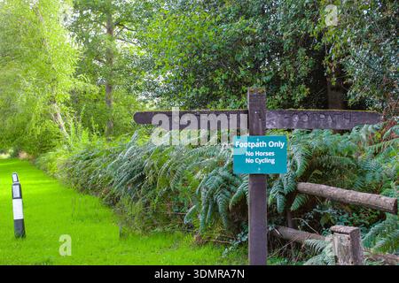 Insegna country Footpath solo su un bosco rustico in un ambiente naturale con vegetazione lussureggiante sullo sfondo. Foto Stock