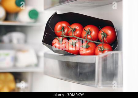 Pomodori freschi conservati nel cassetto frigorifero. Conservazione sana delle verdure e concetto di freschezza naturale degli alimenti negli interni della cucina. Foto Stock
